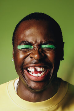 Laughing man portrait in the studio with bold makeup and a joyful expression