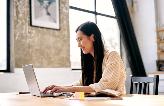 Young woman working on laptop at home office desk.