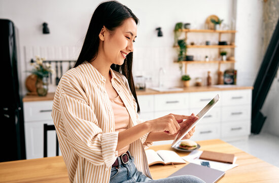 Young woman using tablet in modern kitchen.