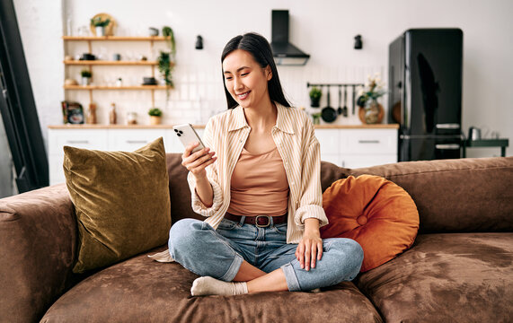Woman using smartphone on sofa at home.