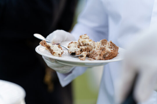 Waiter in white gloves holding a plate of fresh tiramisu dessert at an event
