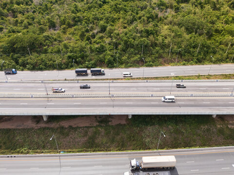 Drone aerial view of an elevated highway crossing lush forest and mountain landscape under dramatic clouds, The modern transportation infrastructure and nature concept
