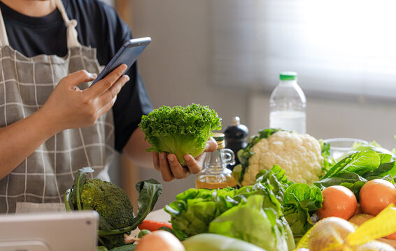 Middle Aged Asian Man Checking Nutrition Information While Choosing Vegetables