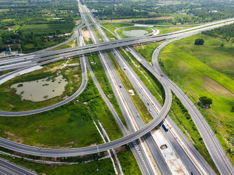 Drone shot a large highway interchange crossing over green farmlands in Thailand