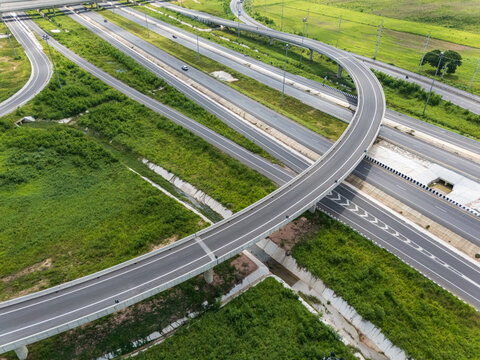 Drone shot a large highway interchange crossing over green farmlands in Thailand