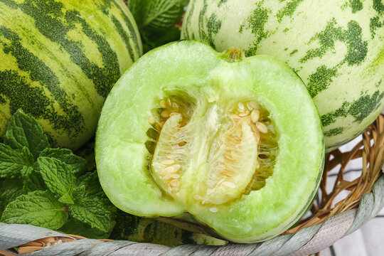 Fresh Winter Melon Cut in Half Showing Seeds and Flesh in Rustic Basket with Mint Leaves