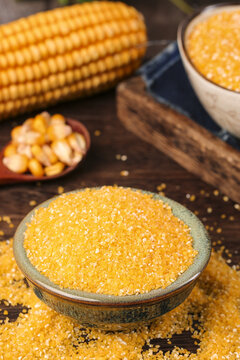 Fresh Yellow Corn Grits and Cornmeal with Corn Cob on Rustic Wooden Table