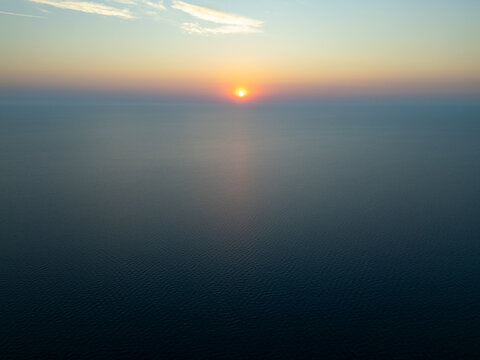 High Aerial View of Golden Sunrise Sunset Over Open Sea Water Horizon