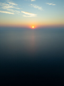 High Aerial View of Golden Sunrise Sunset Over Open Sea Water Horizon