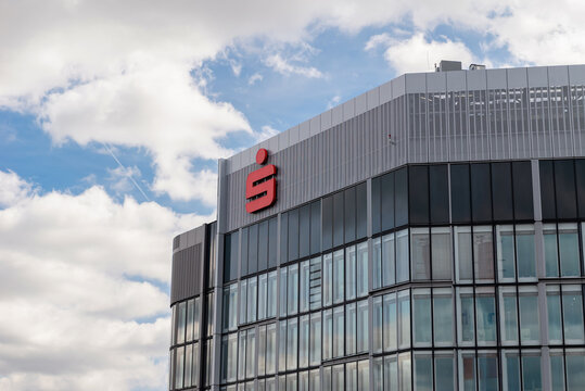 FRANKFURT, GERMANY - APRIL 4, 2026: A low-angle view of the Sparkasse corporate logo on the facade of a modern glass office building against a blue sky with clouds
