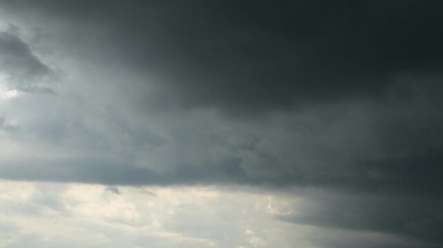 time lapse of overcast sky with dense grey cumulus clouds and small patch of bright sky above