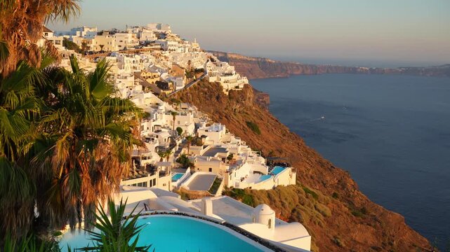 White architecture in Santorini island, Greece. Luxury swimming pool with blue water. Blue sea and the blue sky at sunset. Panoramic view of the island. Travel and summer vacation concept. 
