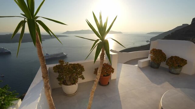 White architecture in Santorini island, Greece. Blue sea and the blue sky at sunset. Beautiful terrace with flowers. Travel and summer vacation concept. 
