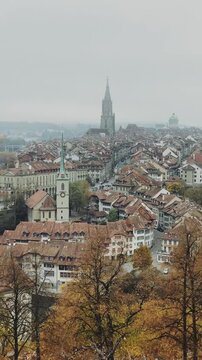 Panning vertical shot of Bern old town on misty autumn day with fog and golden foliage, Bern, Switzerland