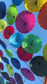 Colorful umbrellas form a vertical outdoor display, festive decoration, summer leisure, vibrant pattern, holiday decoration.