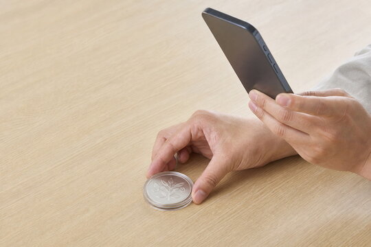 スマートフォンで記念硬貨を撮影するオンライン事前査定