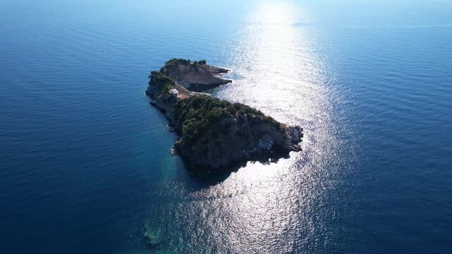Drone aerial of a Aliki Beach secluded Mediterranean bay on Thassos, Greece with clear blue water, sandy shore, paddleboards, swimmers and stunning natural scenery.