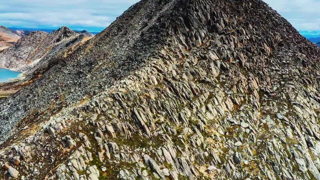 A cinematic low-altitude drone tracking shot capturing the rugged, narrow granite spine of the Knife Edge Trail on Mount Katahdin.