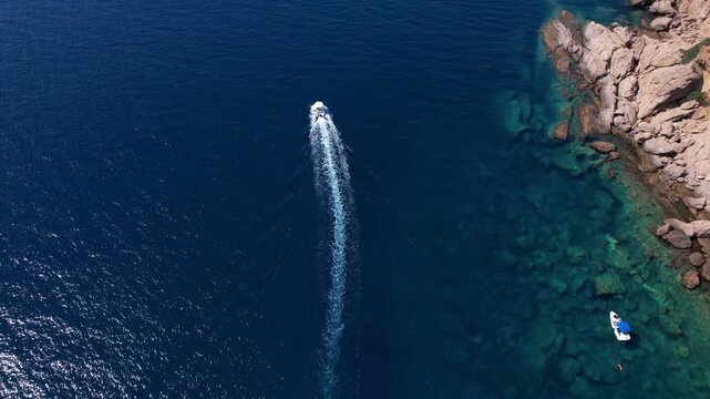 Drone aerial of a Aliki Beach secluded Mediterranean bay on Thassos, Greece with clear blue water, sandy shore, paddleboards, swimmers and stunning natural scenery.