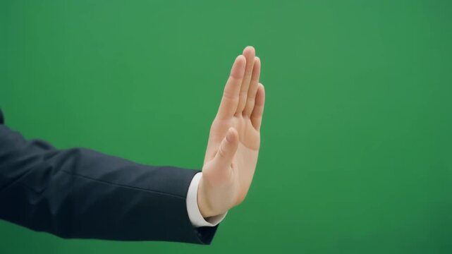 Professional corporate hand forming a stop gesture against a green screen for security warnings, compliance presentations, and motion graphics safety overlays.