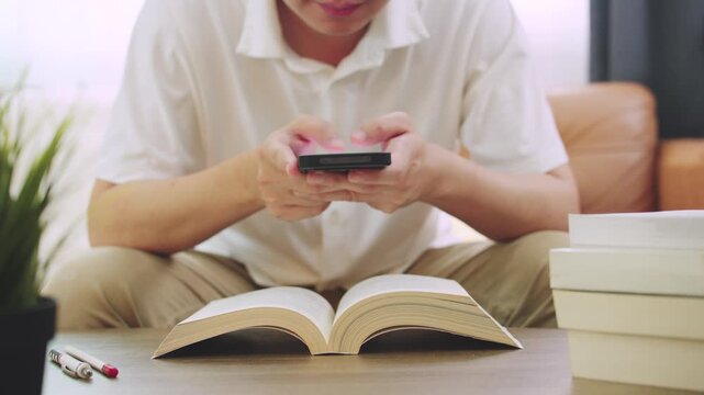 Student Distracted by Mobile Phone While Studying and Reading Book at Home.