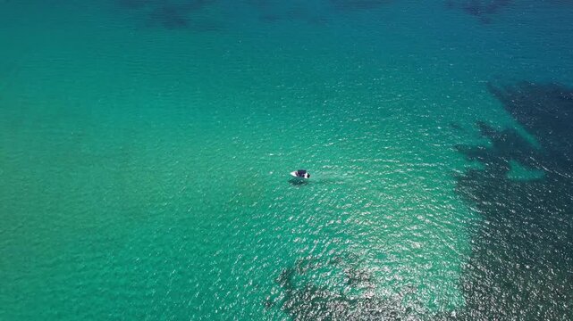 Aerial drone view of a powerful speed boat gliding across crystal-clear turquoise water, creating a striking white wake. Perfect representation of luxury travel, freedom, summer adventure.