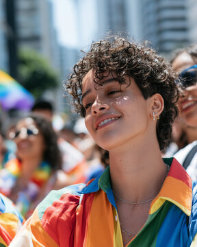 Portrait of a smiling person with curly hair celebrating during the vibrant and colorful Parade LGBT Sao Paulo street event