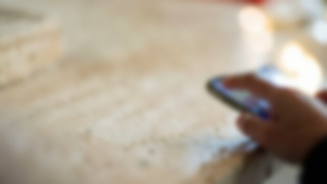 Blurred person using smartphone on travertine table for fintech