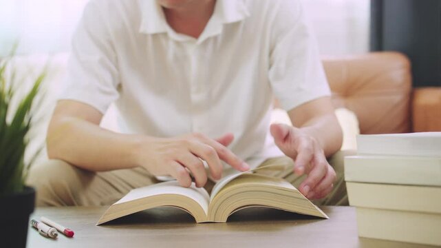 Young Man Reading Research and Flipping Book Pages for Education and Research Concept.