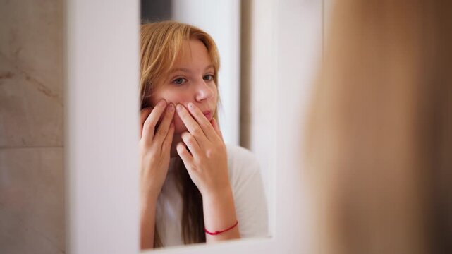 Teenage girl struggling with hormonal acne while examining facial blemishes in bathroom mirror. Daily skincare routine puberty, acne-prone skin, dermatological concerns, adolescent personal care