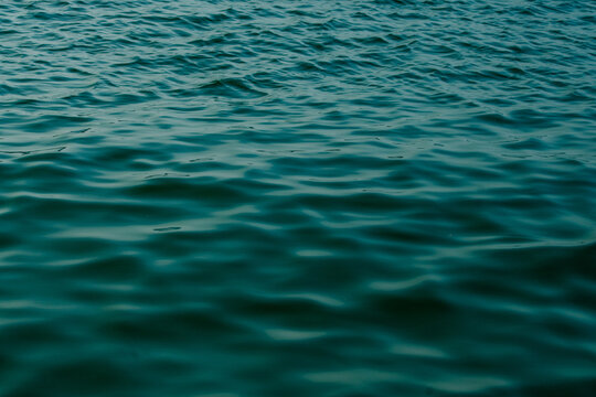 Ripple texture on deep teal blue water surface under daylight.