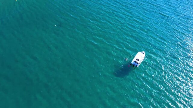 Aerial drone view of a powerful speed boat gliding across crystal-clear turquoise water, creating a striking white wake. Perfect representation of luxury travel, freedom, summer adventure.