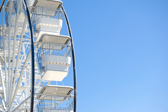 White Ferris wheel cabins with clear blue sky in the background.