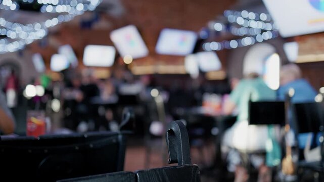 Blurred cafe interior with foreground chair back, seated patrons, warm ambient lights