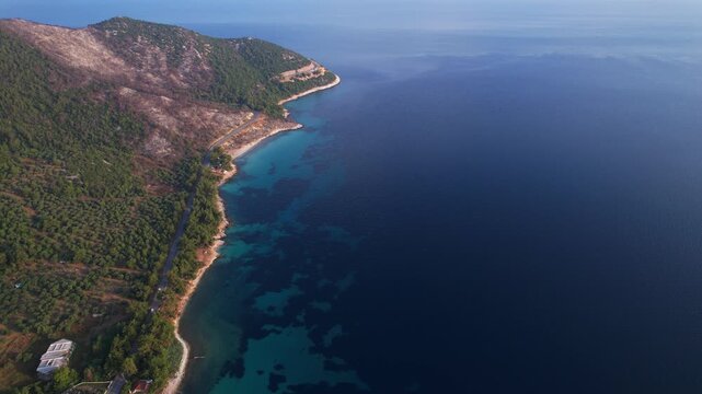 Beautiful aerial view of a sandy beach with crystal clear sea, turquoise water and visitors enjoying swimming and paddleboarding on Thassos Island, Greece.