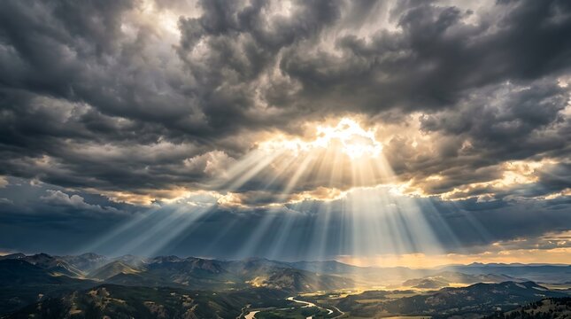 Dramatic sunbeams breaking through dark storm clouds over mountain valley landscape at sunset