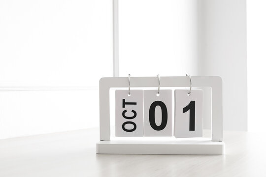White wooden flip calendar showing October 1st date on table. Concept of Q4 start, autumn season, and time management.