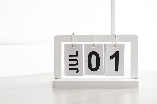 White wooden flip calendar showing July 1st date on table. Concept of mid year start, Canada Day, and time management.