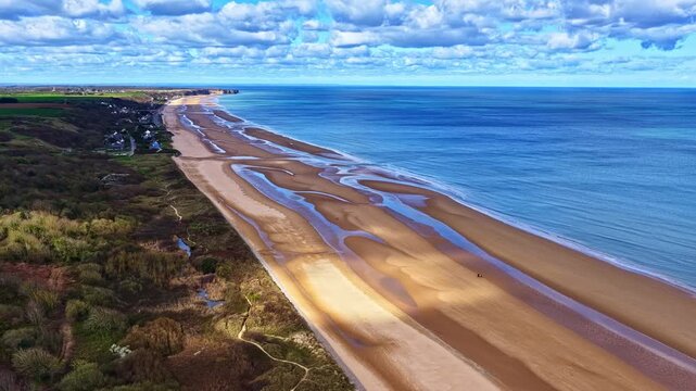 Aerial view of the sandy coastline and tidal flats with dunes and vegetation along the Atlantic shore in France.