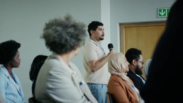 A speaker stands to address a diverse and attentive audience during a professional conference or seminar, fostering an environment of learning and engagement.