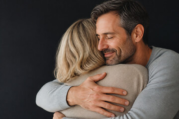 Fototapeta premium A middle-aged couple embracing affectionately against a dark background.