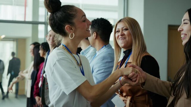 Professionals engage in friendly networking, shaking hands and smiling at a business event. The atmosphere is collaborative and welcoming for attendees.