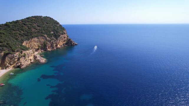 Aerial view of a fast motor yacht cutting through crystal-clear blue water. Vibrant textures, dynamic waves, powerful motion create the perfect visual for themes of luxury, freedom, vacation.