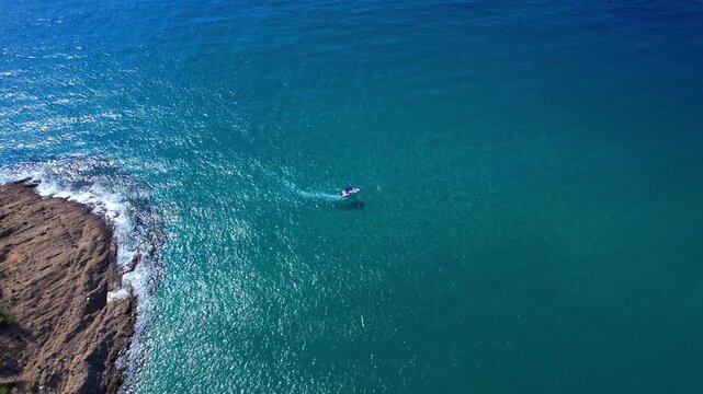 Aerial drone view of a powerful speed boat gliding across crystal-clear turquoise water, creating a striking white wake. Perfect representation of luxury travel, freedom, summer adventure.