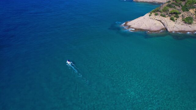 Aerial drone view of a powerful speed boat gliding across crystal-clear turquoise water, creating a striking white wake. Perfect representation of luxury travel, freedom, summer adventure.