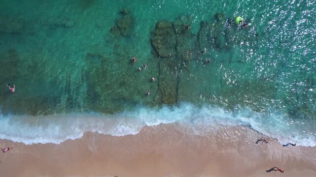 Aerial drone of a peaceful beach in Thassos, Greece, featuring transparent turquoise water, paddleboards, swimmers and a beautiful Mediterranean coastline.