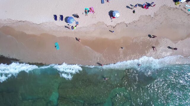 Aerial drone of a peaceful beach in Thassos, Greece, featuring transparent turquoise water, paddleboards, swimmers and a beautiful Mediterranean coastline.