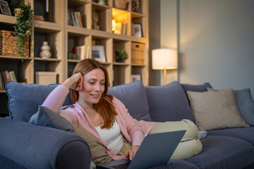 Young woman relaxing on sofa using laptop at home © Migma_Agency