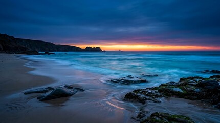 Obraz premium Beautiful sunset over the ocean with dark rocky beach