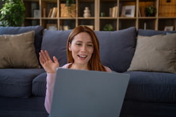 Woman waving during remote video call on laptop at home © Migma_Agency
